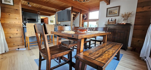 dining space with light wood-type flooring, beamed ceiling, and wooden ceiling