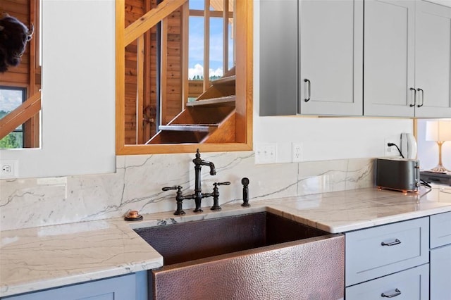 kitchen with light stone counters, a sink, and tasteful backsplash