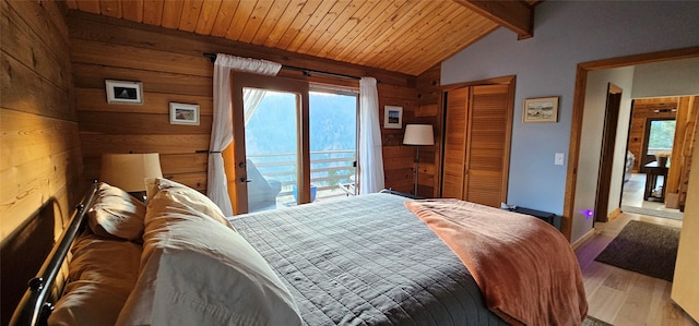 bedroom featuring vaulted ceiling with beams, wooden ceiling, wood walls, light wood-style floors, and access to outside