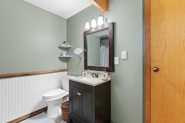 full bathroom featuring wainscoting, vanity, and toilet