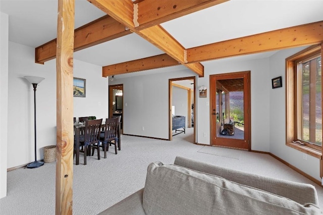 living room featuring carpet floors, a wealth of natural light, baseboards, and beam ceiling