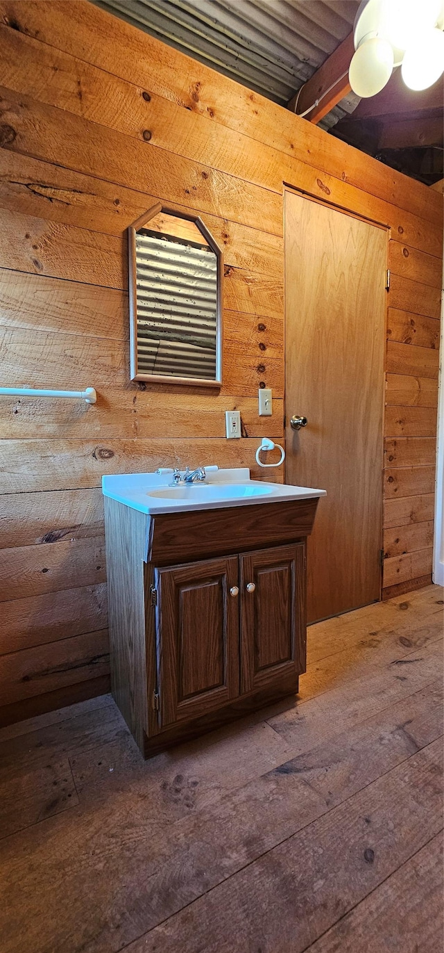 bathroom with wood walls, wood finished floors, and vanity