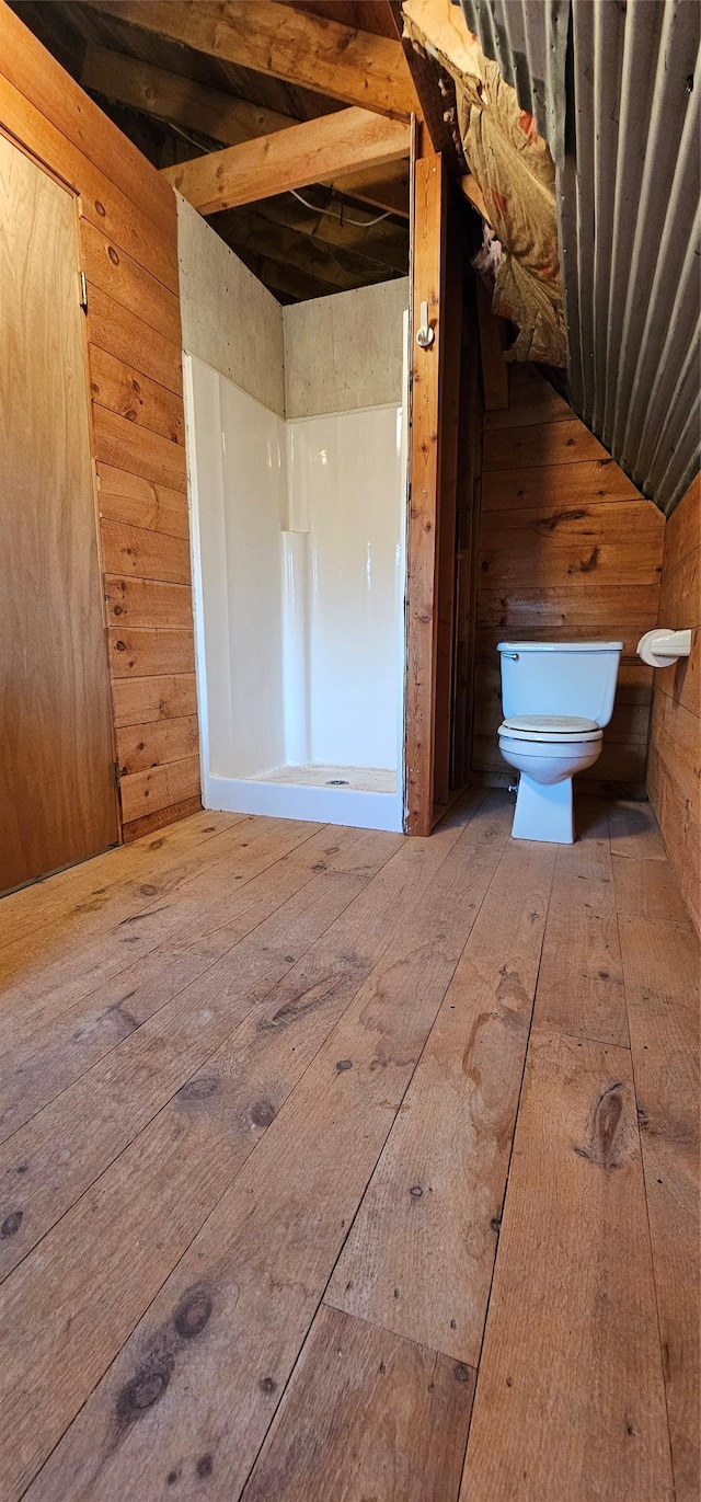 bathroom featuring lofted ceiling, wood walls, toilet, and wood finished floors