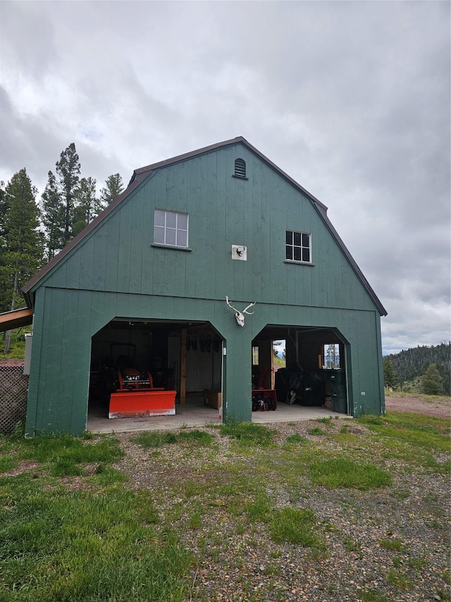 rear view of property featuring a detached garage, a pole building, and an outbuilding