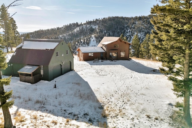 snowy aerial view featuring a mountain view and a view of trees