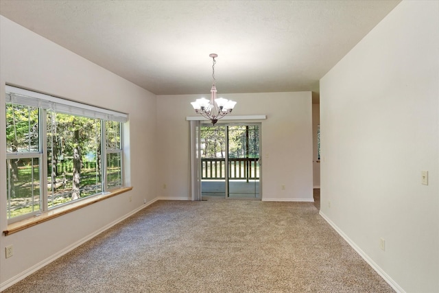 carpeted spare room featuring an inviting chandelier