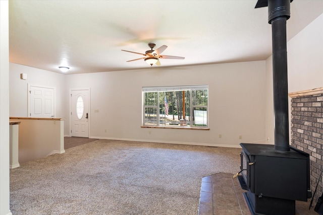 unfurnished living room featuring carpet, ceiling fan, and a wood stove