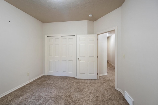 unfurnished bedroom featuring a closet, light colored carpet, and a textured ceiling