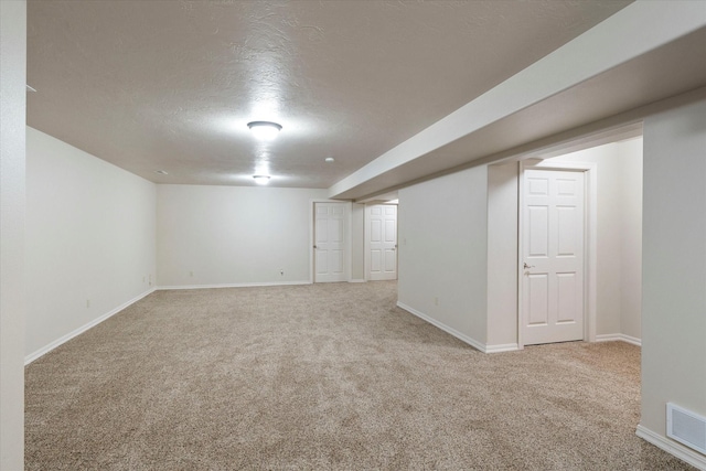 basement featuring a textured ceiling and light carpet