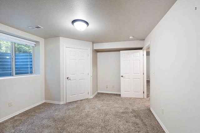 unfurnished bedroom with light carpet, a textured ceiling, and a closet