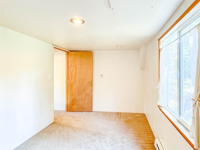 unfurnished room with baseboard heating and carpet