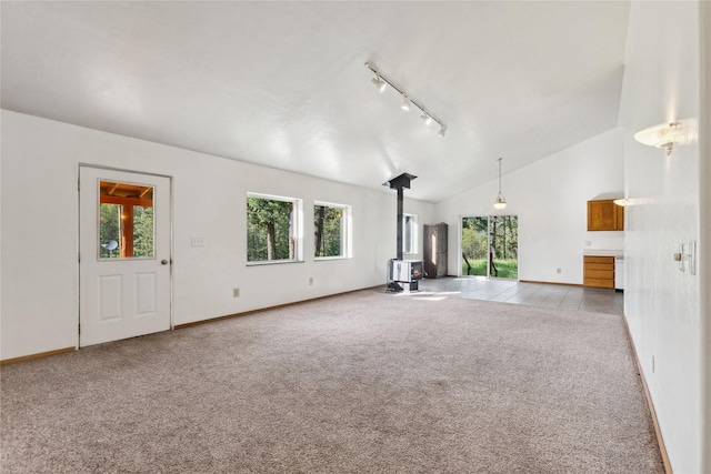 8100 US Highway 2 W, Marion, MT 59925 - unfurnished living room featuring a wood stove, rail lighting, carpet, plenty of natural light, and high vaulted ceiling