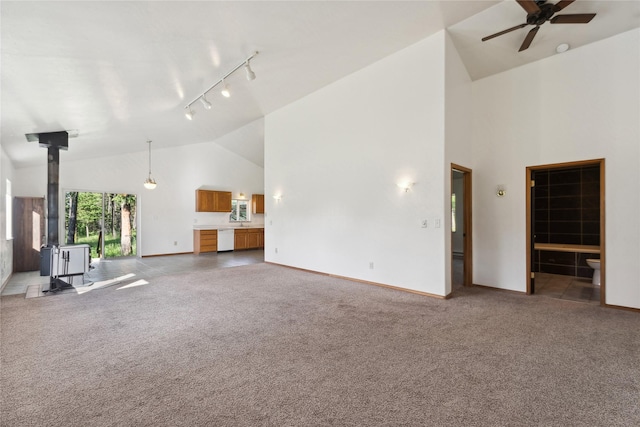 8100 US Highway 2 W, Marion, MT 59925 - unfurnished living room with a wood stove, high vaulted ceiling, carpet, a ceiling fan, and track lighting