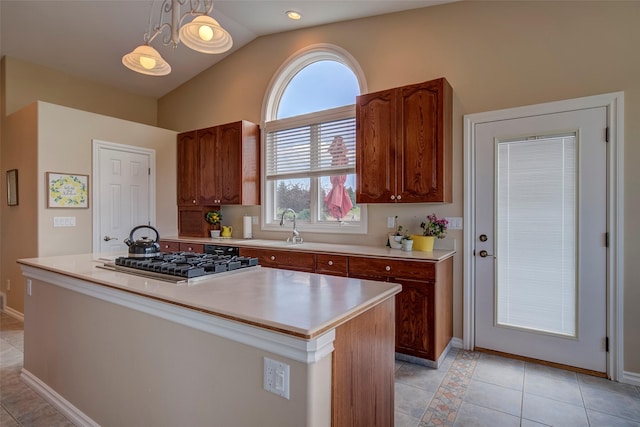 kitchen featuring pendant lighting, a center island, light tile patterned flooring, vaulted ceiling, and stainless steel gas stovetop