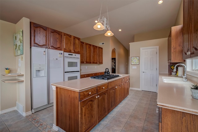 kitchen with sink, light tile patterned floors, a kitchen island, pendant lighting, and white appliances