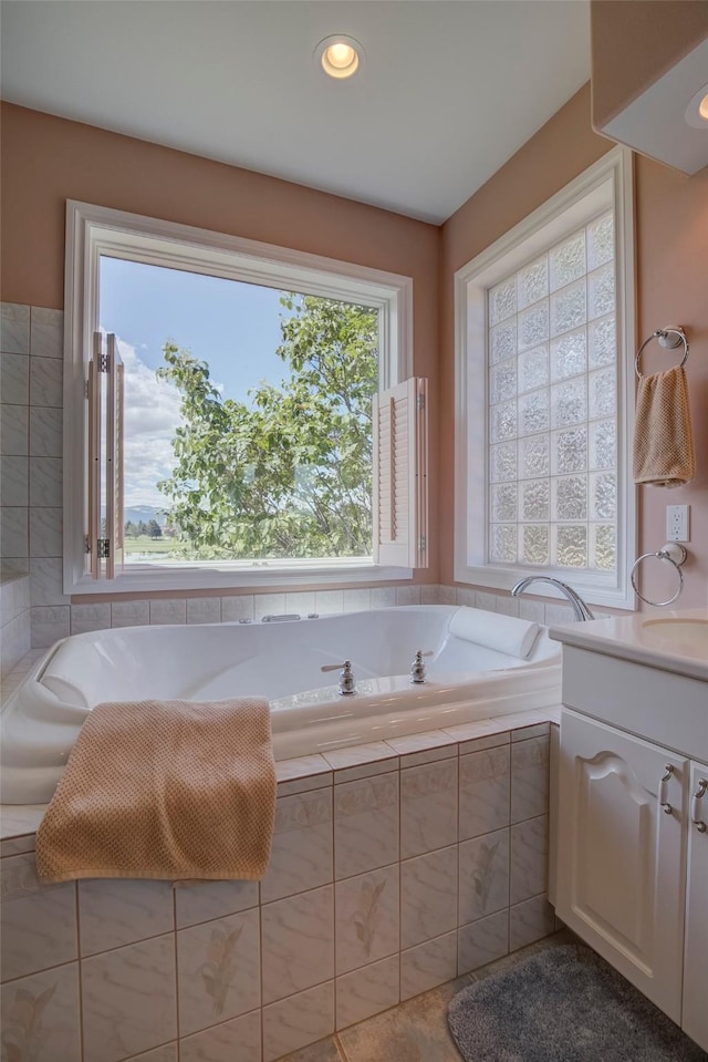 bathroom featuring a relaxing tiled tub and vanity