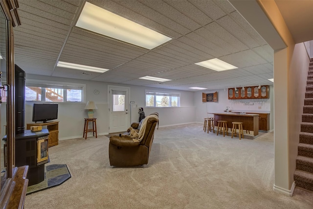 living room with bar area, light colored carpet, a healthy amount of sunlight, and a wood stove