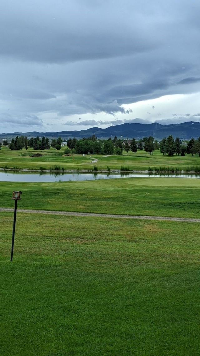 view of property's community featuring a water and mountain view and a lawn