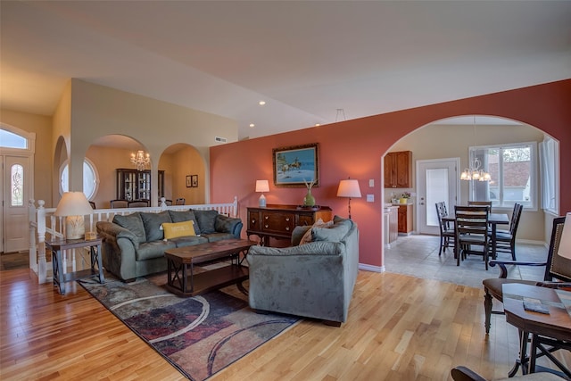 living room featuring an inviting chandelier, light hardwood / wood-style flooring, and vaulted ceiling