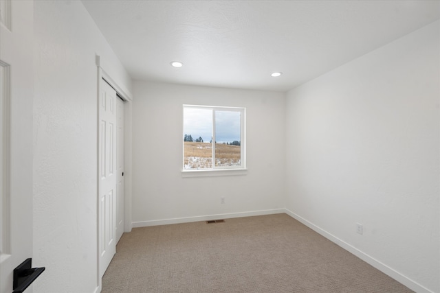 unfurnished bedroom featuring light carpet and a closet