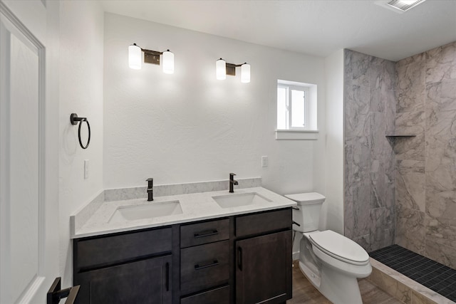 bathroom with vanity, toilet, wood-type flooring, and tiled shower