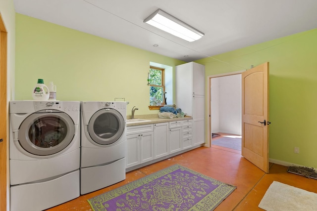 laundry room with washing machine and dryer, cabinets, and sink