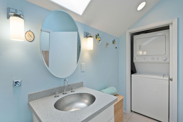 bathroom featuring sink, tile patterned floors, stacked washer and dryer, and vaulted ceiling