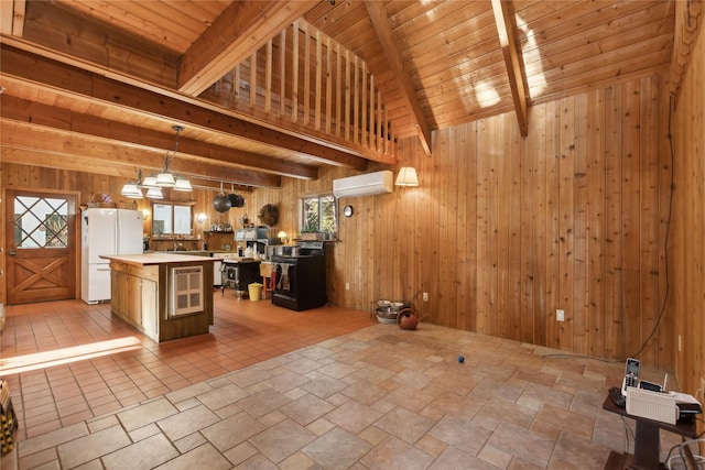 kitchen with wooden walls, a center island, hanging light fixtures, freestanding refrigerator, and a wall mounted AC