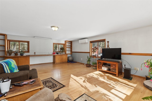 living area with light wood finished floors and an AC wall unit