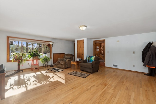 living room featuring light wood-style flooring, visible vents, and baseboards