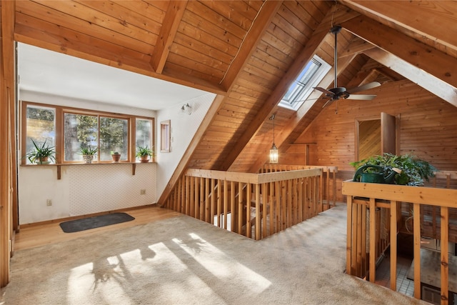 additional living space with vaulted ceiling with skylight, wooden ceiling, and light colored carpet