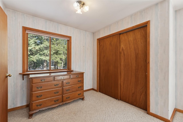 bedroom featuring a closet, light carpet, baseboards, and wallpapered walls