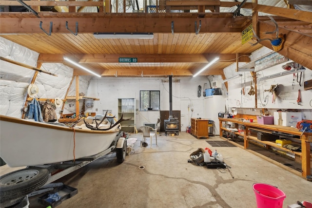 interior space featuring concrete flooring, a workshop area, and a wood stove