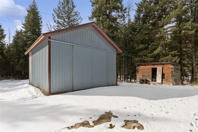 snow covered structure featuring a pole building and an outdoor structure