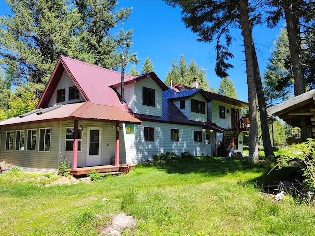 view of front of home with covered porch, metal roof, a chimney, and a front yard