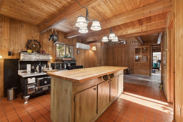 kitchen featuring light tile patterned floors, butcher block counters, hanging light fixtures, wood walls, and a wall mounted AC