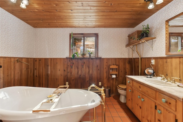 bathroom with a wainscoted wall, a freestanding bath, and wallpapered walls