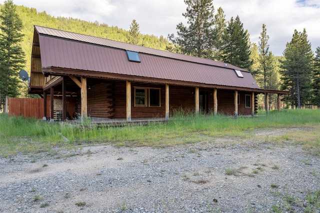 view of front facade with metal roof, log exterior, and a gambrel roof