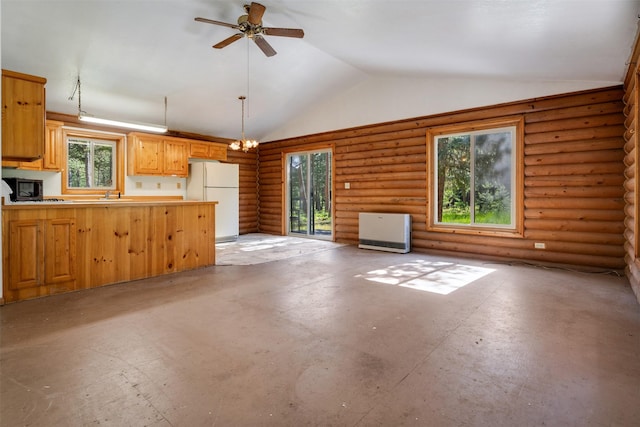 kitchen featuring freestanding refrigerator, hanging light fixtures, light countertops, rustic walls, and vaulted ceiling