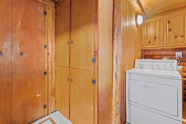 clothes washing area featuring wooden walls, cabinet space, wooden ceiling, and washer / dryer