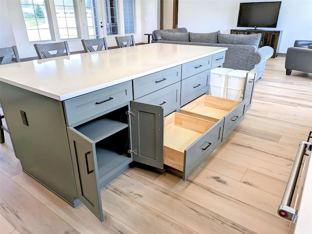 585 Dayton St SE, Ronan, MT 59864 - kitchen featuring light wood-style flooring, gray cabinetry, a center island, light countertops, and a breakfast bar