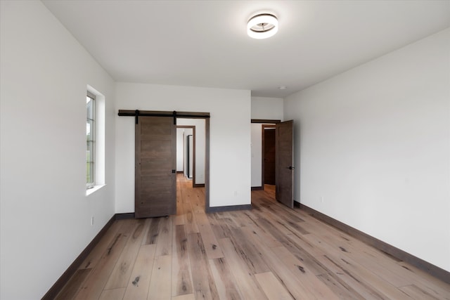 unfurnished bedroom with a barn door and hardwood / wood-style flooring