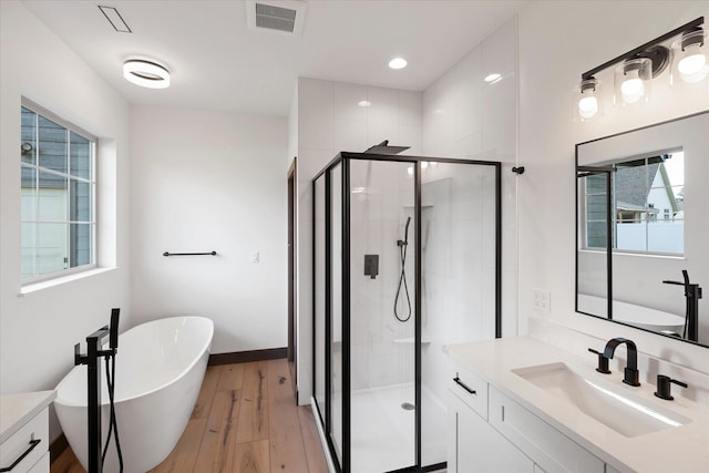585 Dayton St SE, Ronan, MT 59864 - full bath featuring vanity, a shower stall, a freestanding tub, and wood finished floors