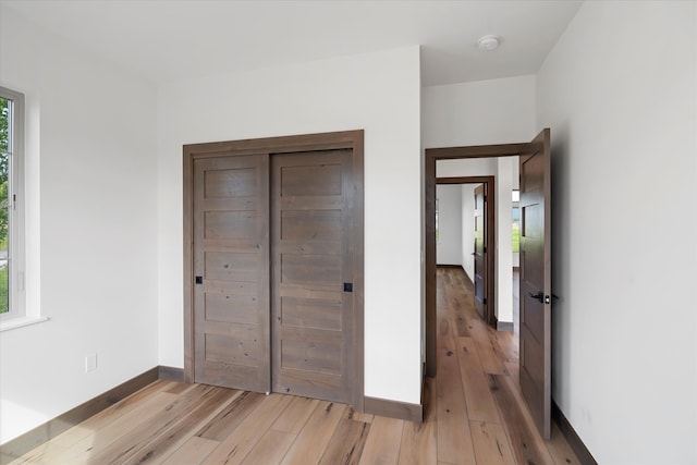 unfurnished bedroom with a closet and light hardwood / wood-style floors