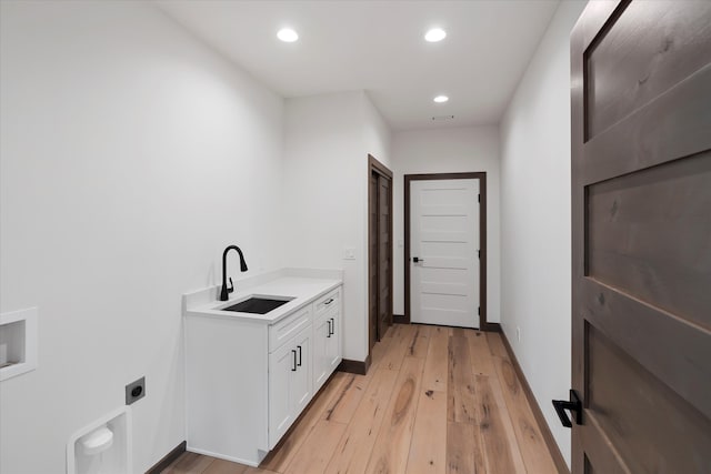 laundry room featuring light hardwood / wood-style floors, hookup for a washing machine, hookup for an electric dryer, sink, and cabinets