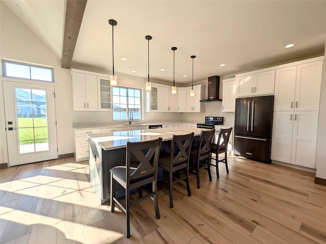 585 Dayton St SE, Ronan, MT 59864 - kitchen with high end refrigerator, wall chimney exhaust hood, light wood finished floors, a center island, and glass insert cabinets