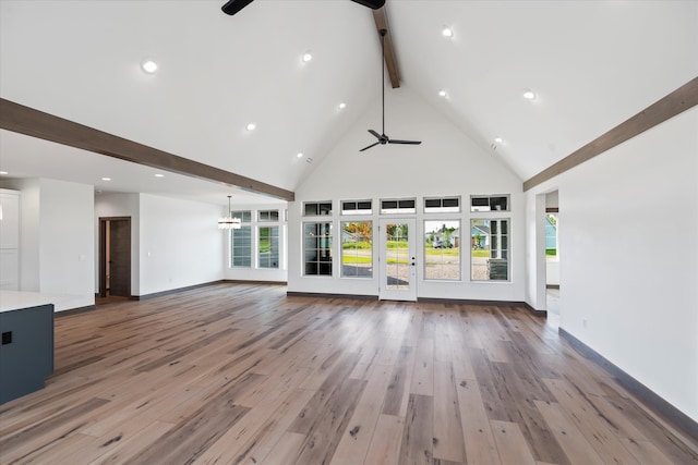 unfurnished living room with beamed ceiling, high vaulted ceiling, hardwood / wood-style flooring, and ceiling fan with notable chandelier