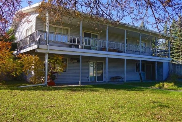 rear view of house featuring a lawn and a balcony