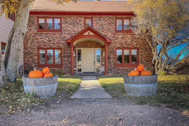 view of front of property with brick siding and roof with shingles