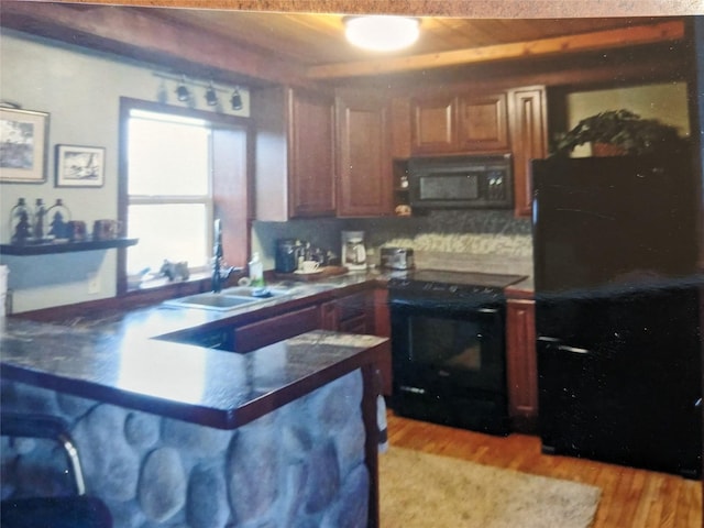 240 Ponderosa Rd, Melrose, MT 59743 - kitchen with black appliances, a sink, a peninsula, light wood-style floors, and dark countertops